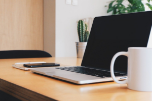Clean office desk with laptop, coffee mug, and a cell phone on top