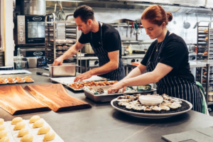 Two chefs plating a meal in a clean kitchen.