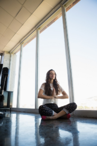 A woman doing yoga while sitting on the floor in her office