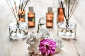 white and purples flower with blurred fragrance bottles in the background.