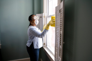 Woman cleaning glass windows with a damp microfiber cloth.